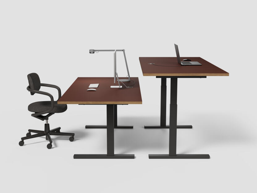 A pair of ATS tables by Faust: one at standard height with an adjacent chair, and the other elevated for a standing work position. The tables have black metal stands with a rectangular profile and Burgundy linoleum tabletops with wooden edges. They includ