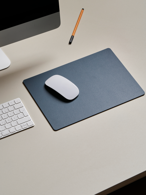 Areal view of a linoleum office table with a Faust small-format PAD Mat in 4179 Smokey Blue, used as a base for a mouse