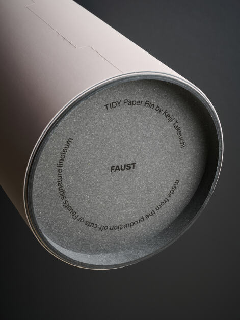 Close-up of the bottom part of the TIDY Paper Bin, showing the bonded leather base with the FAUST branding logo and a sentence describing the project's process.