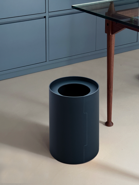 TIDY Paper Bin by Keiji Takeuchi in Smokey Blue linoleum next to a table with wooden legs in a home-office set-up