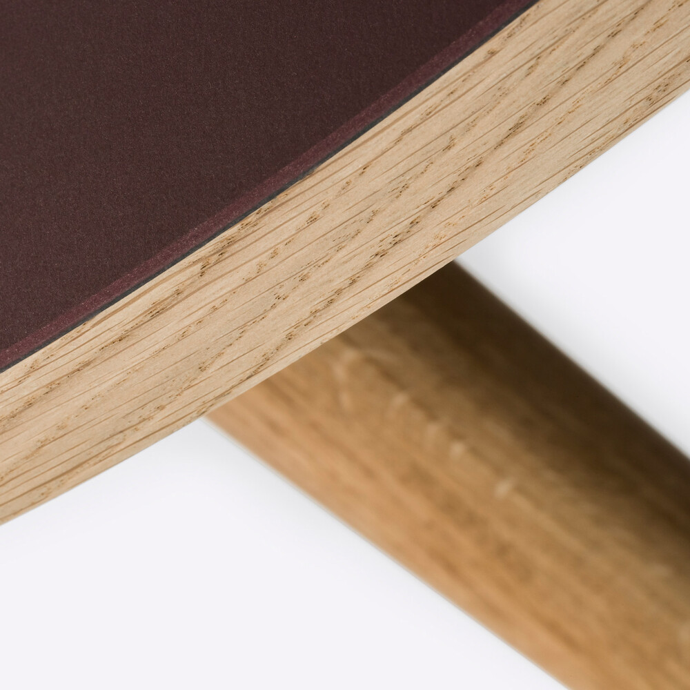 Detail of a round wooden tabletop lined in Burgundy linoleum and mounted on MT2 oak legs by Murken Hansen for FAUST Linoleum