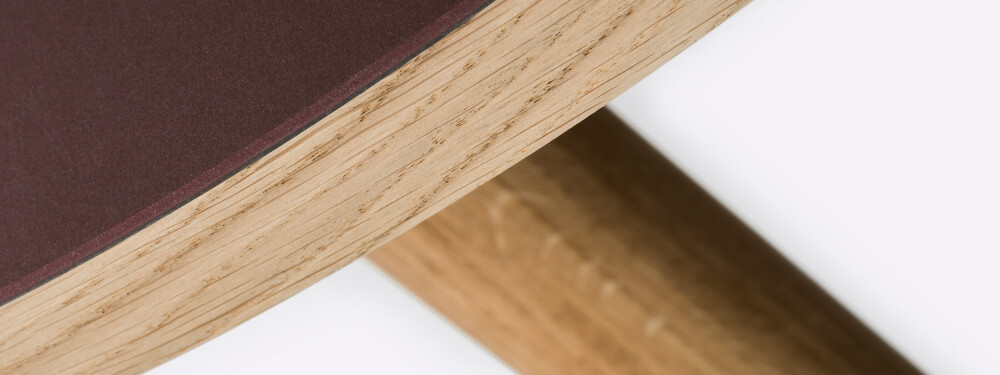 Detail of a round wooden tabletop lined in Burgundy linoleum and mounted on MT2 oak legs by Murken Hansen for FAUST Linoleum