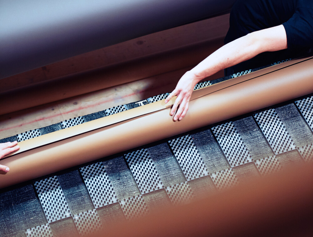 aust Linoleum Schreiner bei der Handhabung einer Linoleum-Rolle während der Tischplattenproduktion